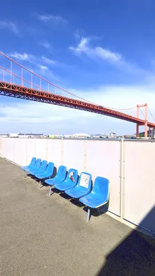 赤い吊り橋を望む待合いの青いベンチ