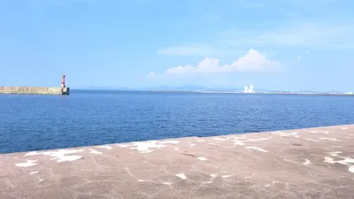 赤い灯台が立つ港の防波堤と夏の海